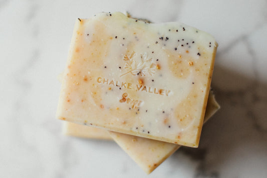 Citrus and poppy soap bars on a marble surface, branded 'Chalke Valley Soaps'.