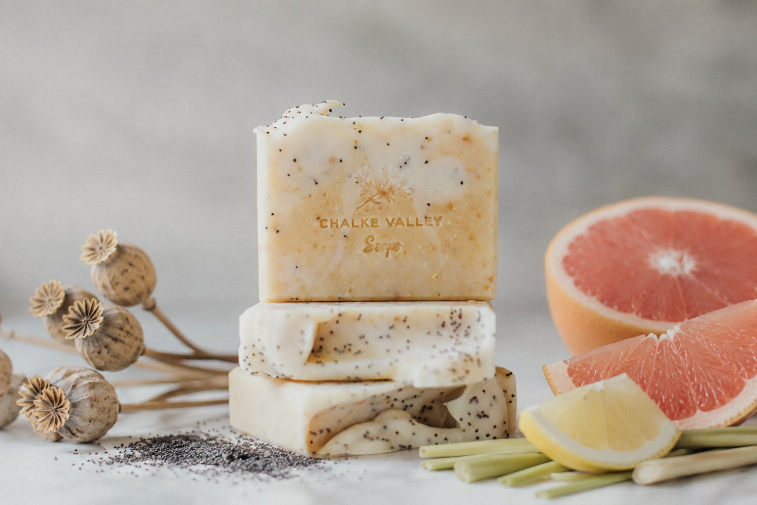 Three bars of Chalke Valley Soaps with a grapefruit and lemon on a neutral background